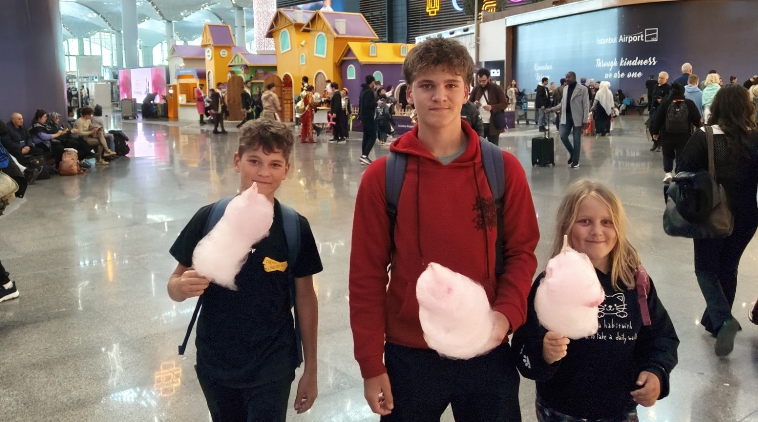 Trije otroci različnih starosti na letališču.