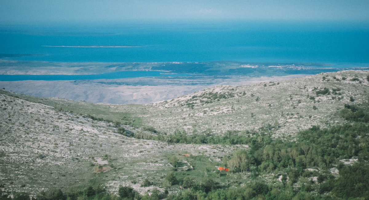 Ruševje in grmiči, v ozadju je modro morje