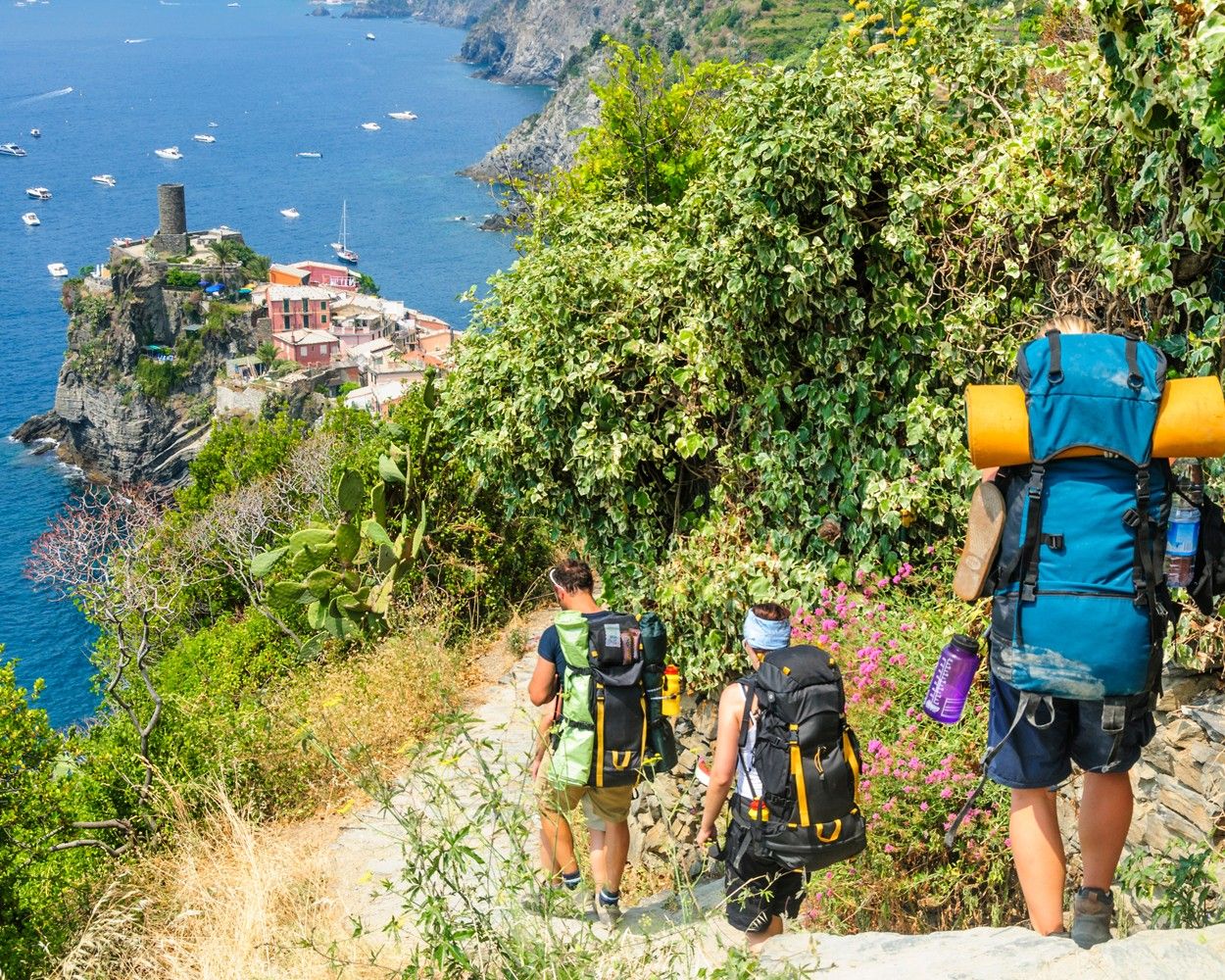 Trije pohodniki se spuščajo proti eni izmed vasic Cinque Terre.