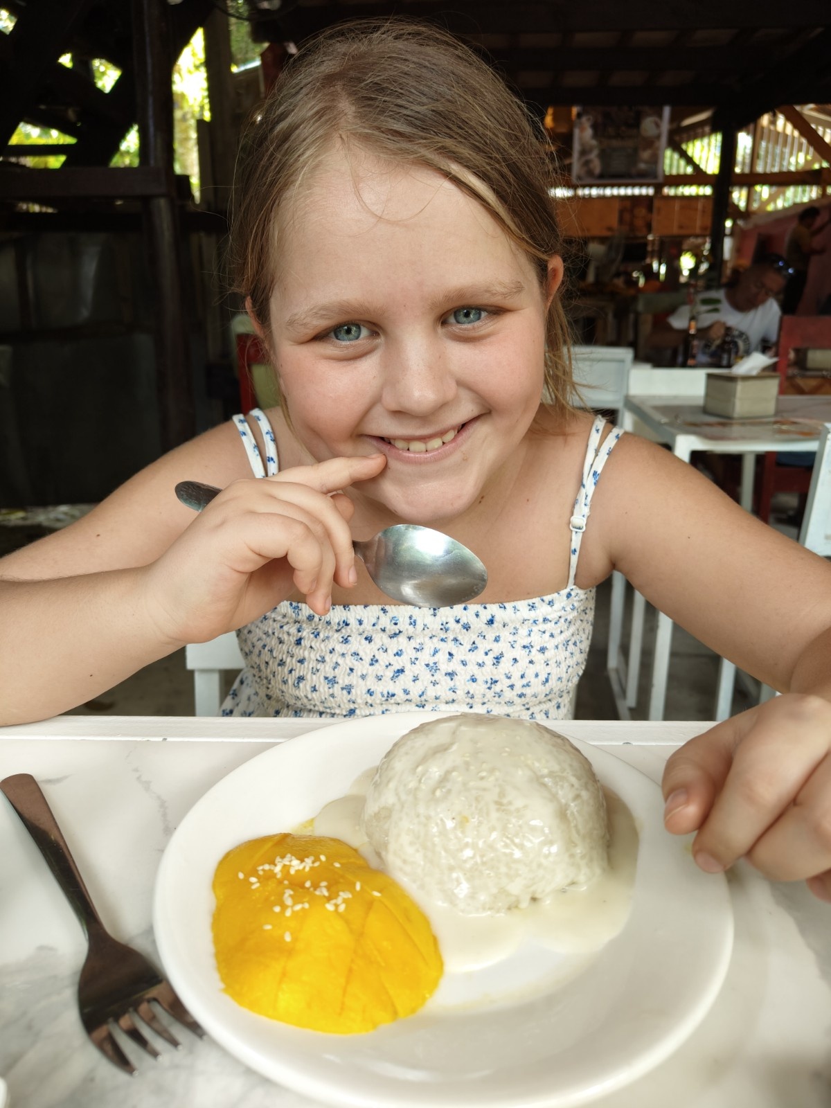 Deklica na počitnicah ima mango na krožniku.