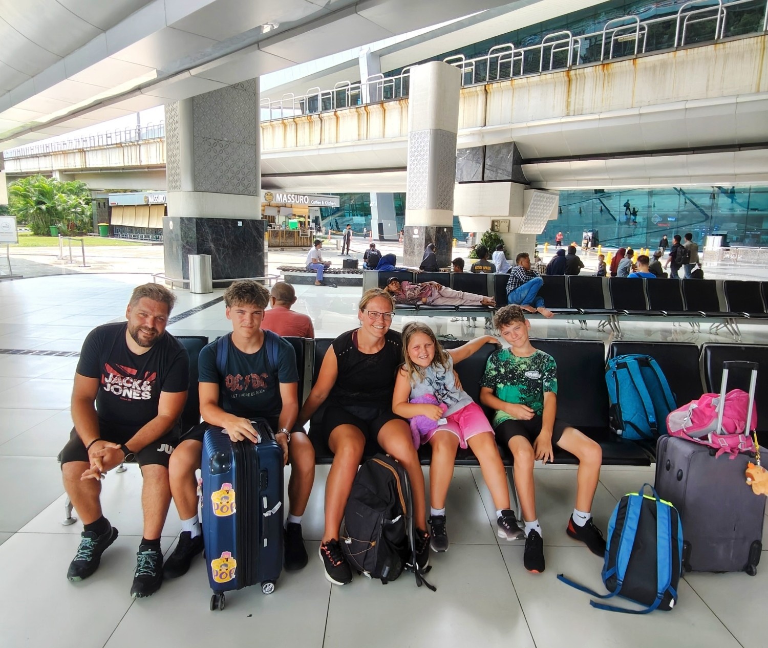 Starši in otroci sedijo na letališču in čakajo na let.