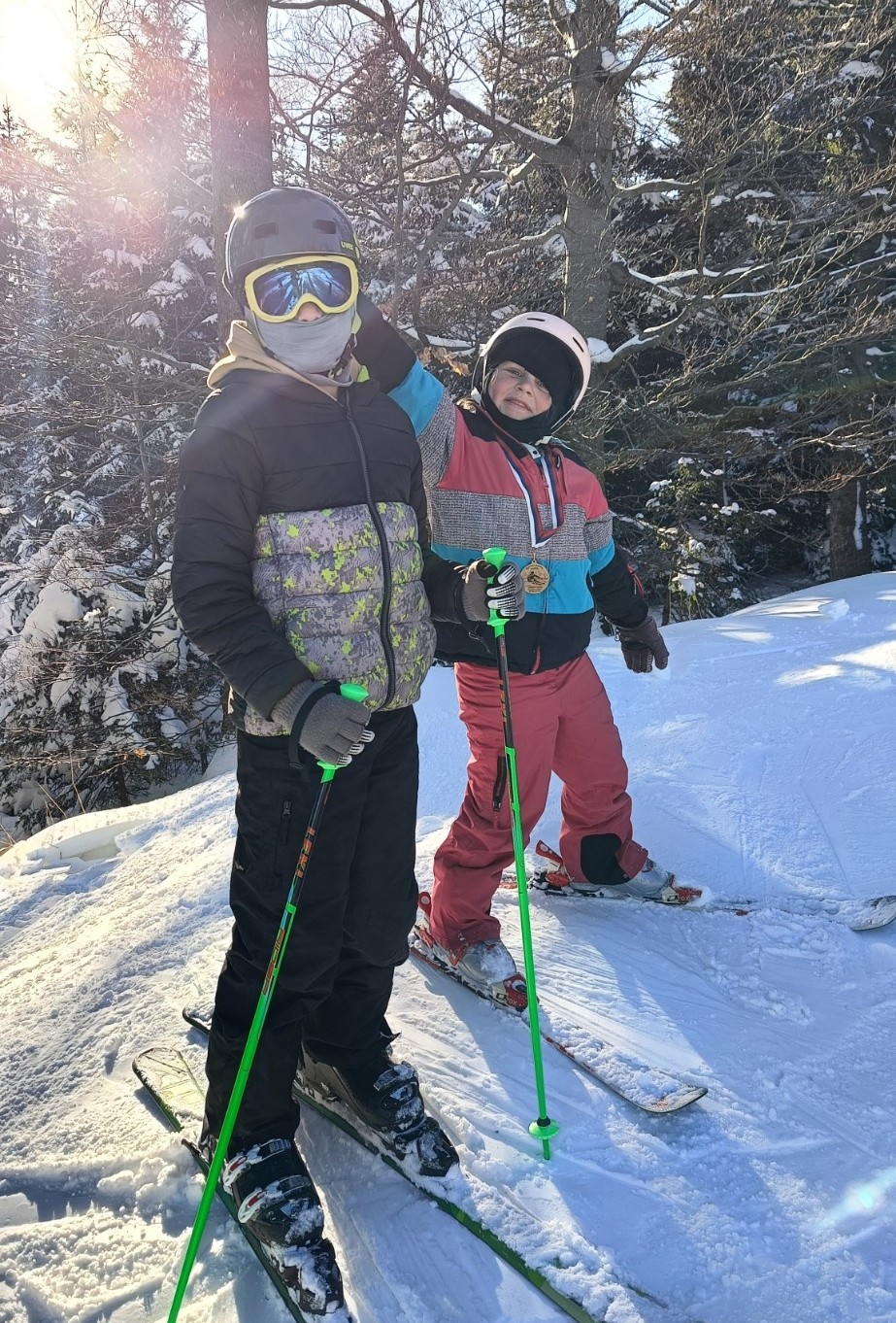 Dva otroka se igrata na smučkah sredi smučišča.