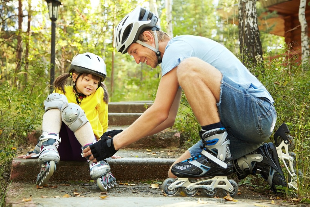 Oče in hčerka se pripravljata na vožnjo z rolerji