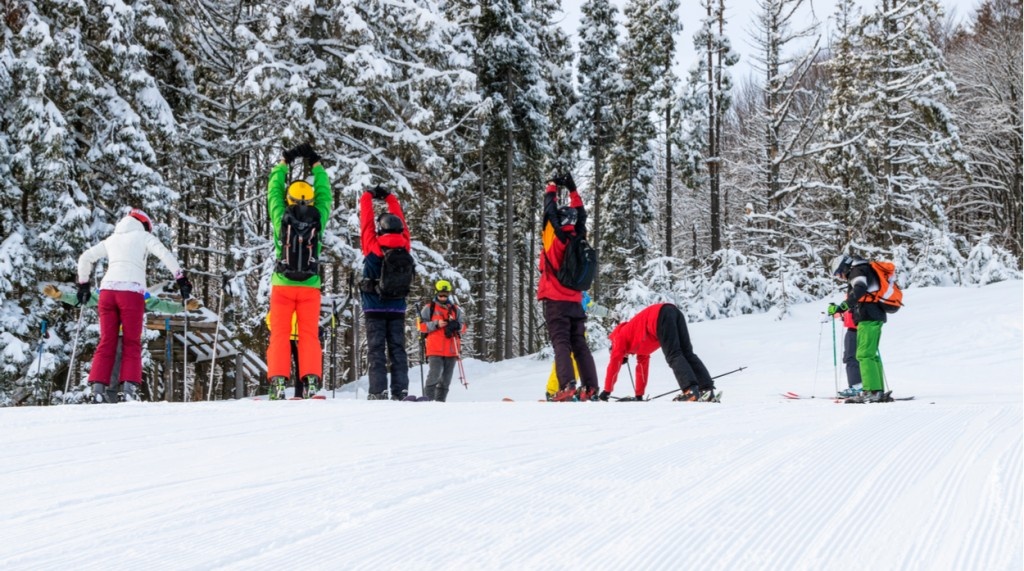 Skupina smučarjev se razteguje in ogreva za smuko