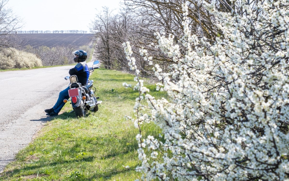 Oseba sedi na motorju ob robu ceste