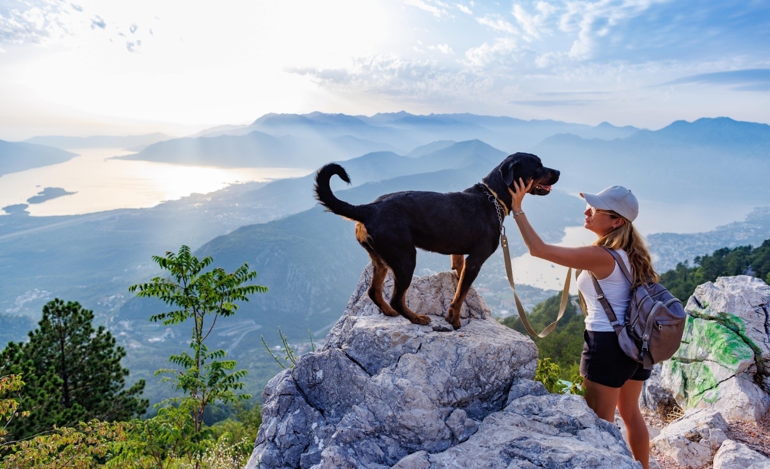 Ženska z rottweiler psom stoji na visokem hribu.
