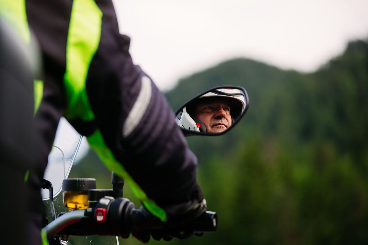 Motorist slikan na motorju, v stranskem ogledalu se vidi njegov obraz.