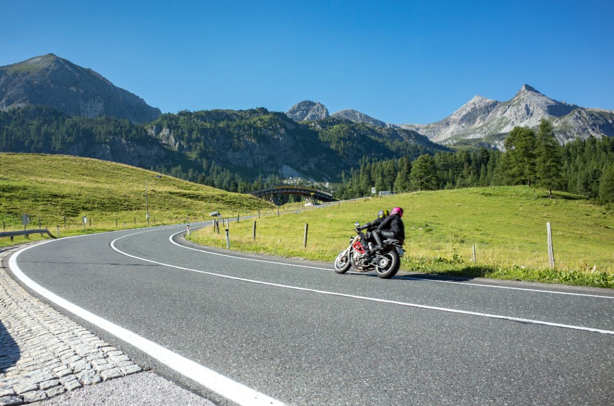 Dve osebi se vozita z motorjem po cesti sredi narave.