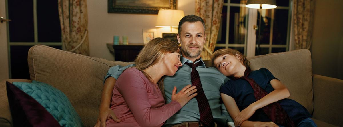 Starša in otrok sedijo na kavču in se objemajo