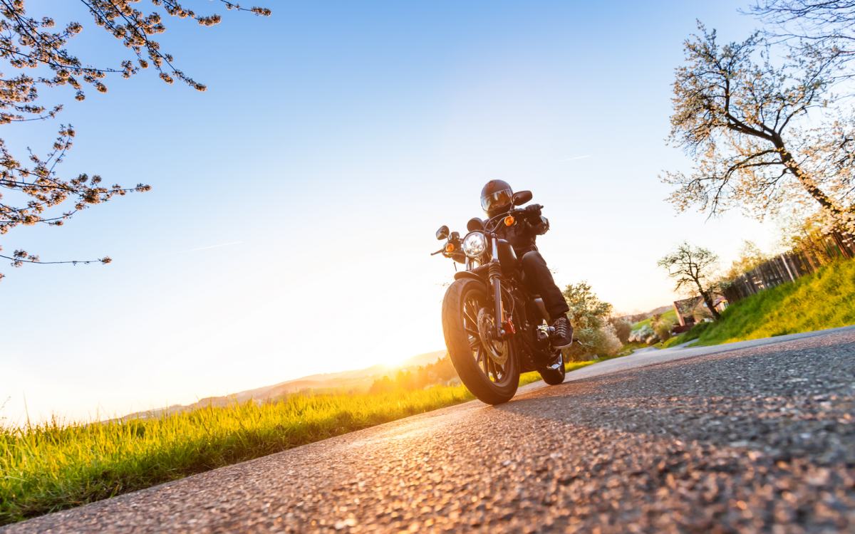 Motorist sedi na motorju sredi prazne ceste.