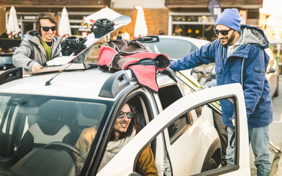 Trije prijatelji pakirajo smučke in ostalo smučarsko opremo v avto.