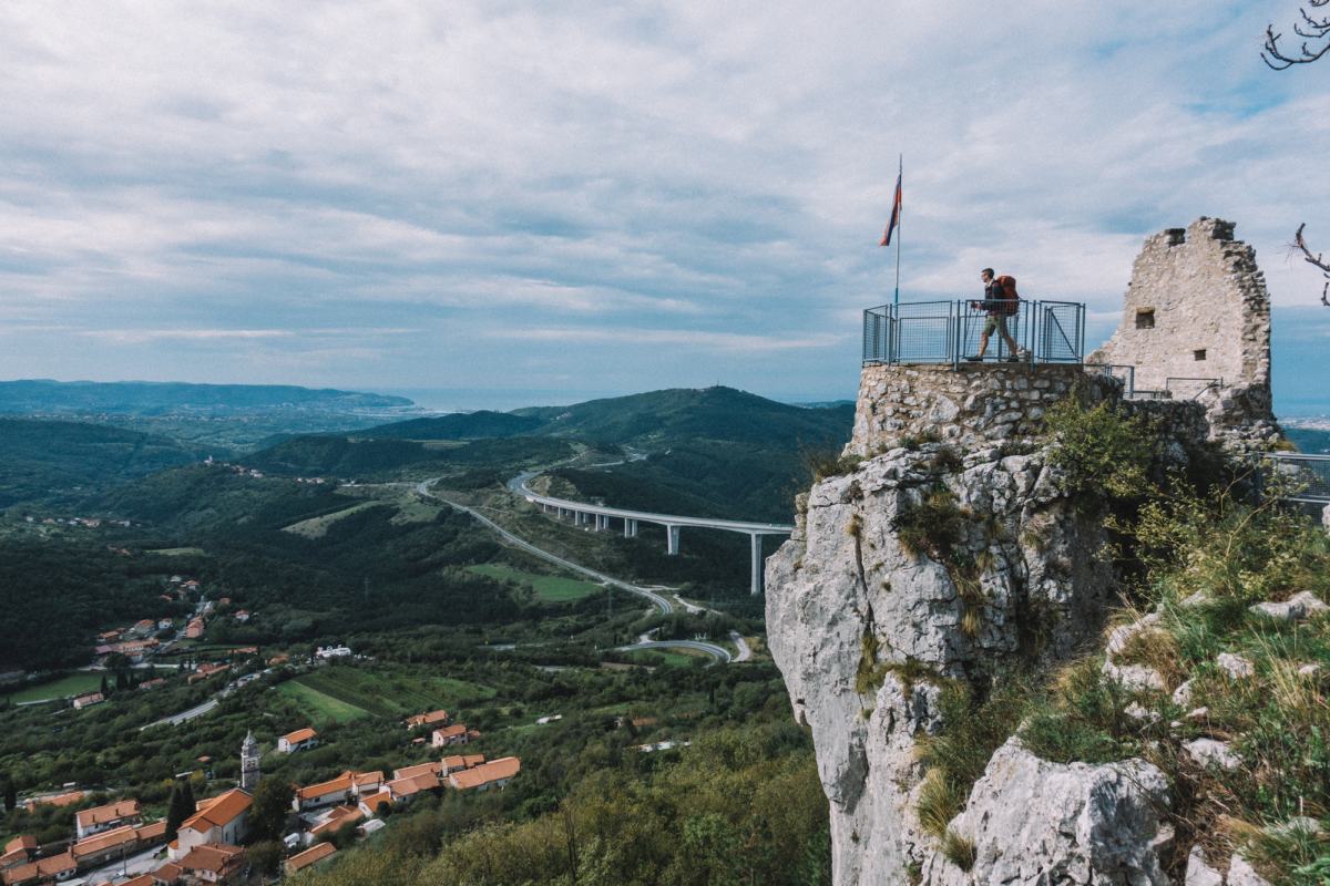 Pohodnik stoji na razgledni točki na vrhu hriba.