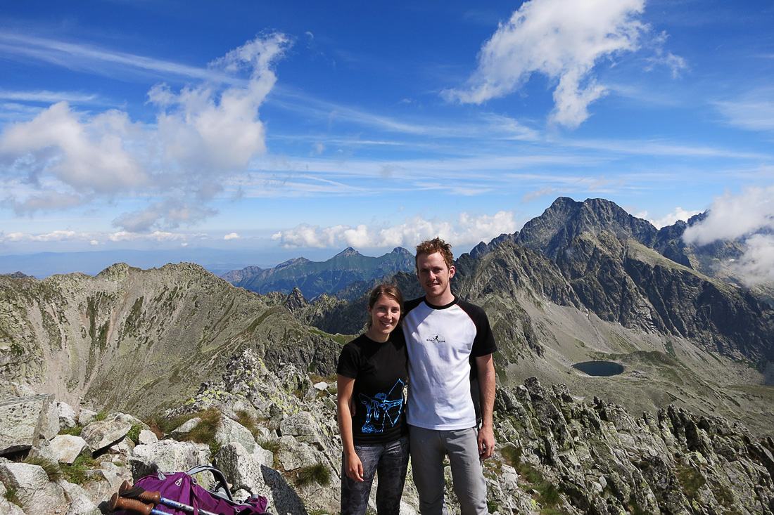 Ženska in moški stojita na vrhu gore.