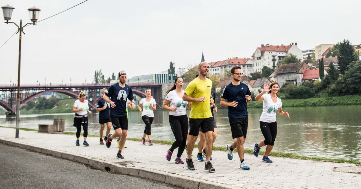 Skupina ljudi skupaj trenira tek ob reki.