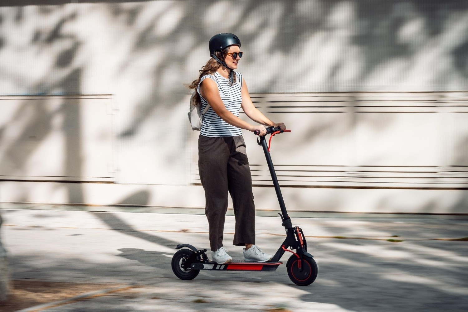 Ženska na električnem skiroju s čelado na glavi.