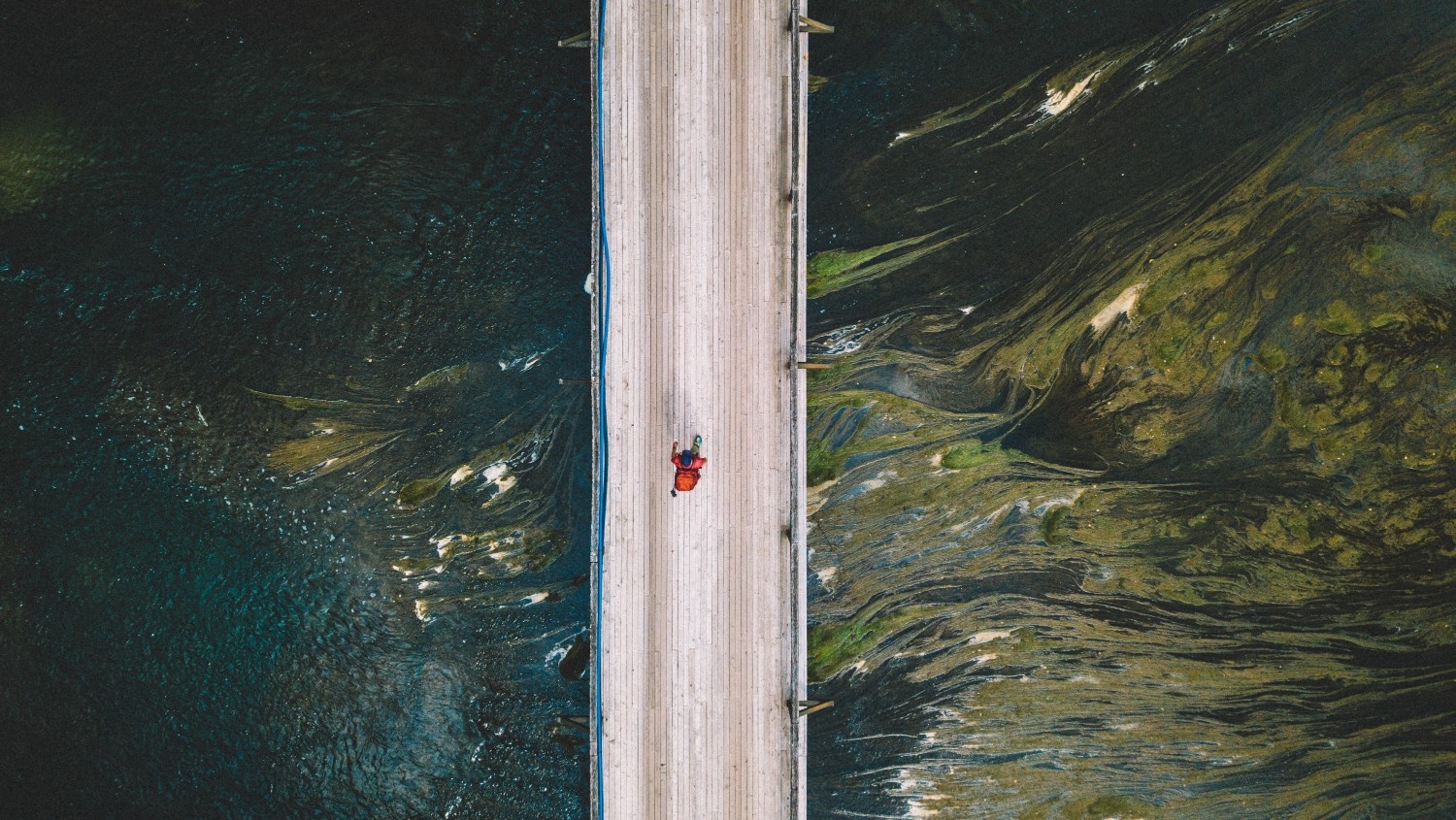 Ptičja perspektiva na pohodnika, ki hodi po mostu nad reko Krko