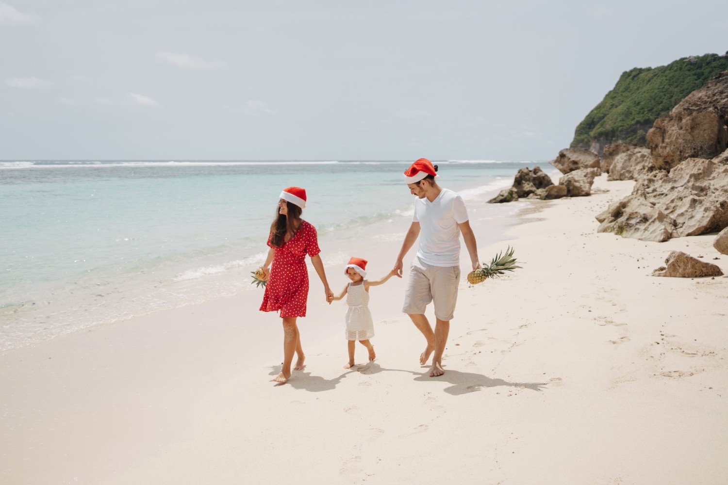 Družina z božičnimi kapami na peščeni plaži