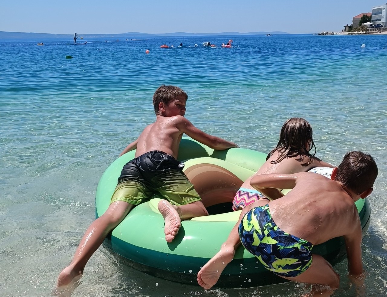 Trije otroci se igrajo v vodi na morju.