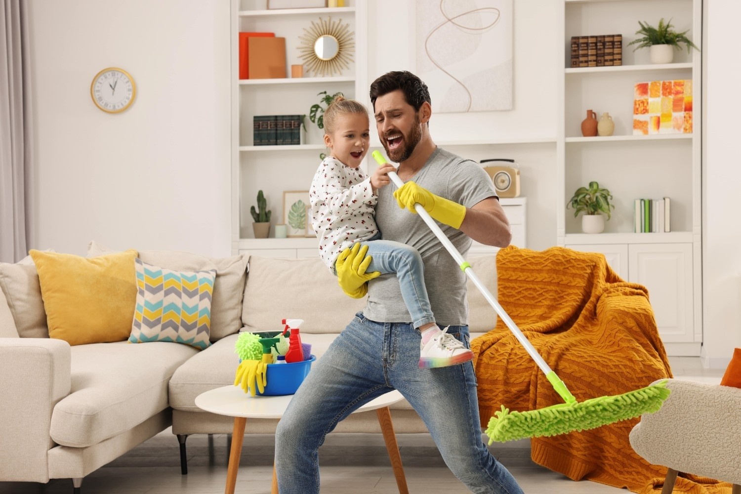 Oče in hčerka veselo pojeta in čistita stanovanje.