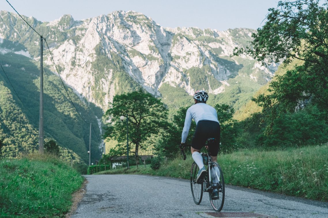 Kolesar na cesti sredi travnikov in gozdov.