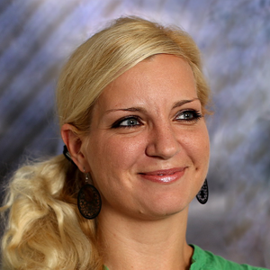 Smehljajoča ženska z dolgimi blond lasmi in okroglimi uhani